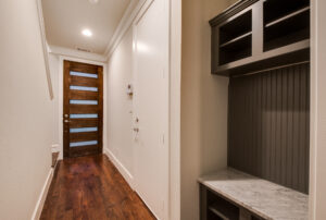 Interior view of the front entry hallway with dark wooden floors and a black shelving unit with a bench seat