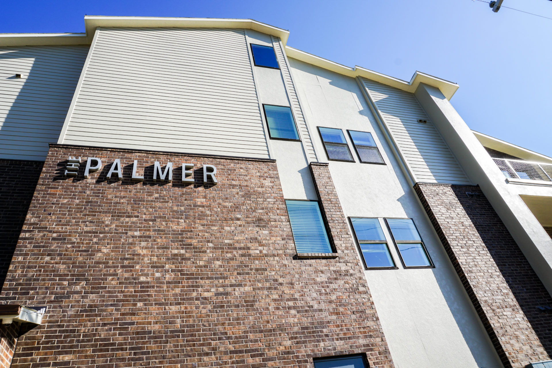 Exterior, close-up view of the red and brown brick with grey lettering that says "The Palmer" on the side of the building
