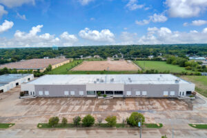 Aerial view of one building in the Suffolk Business Park with grey and white siding, entrance ramps, and loading docks