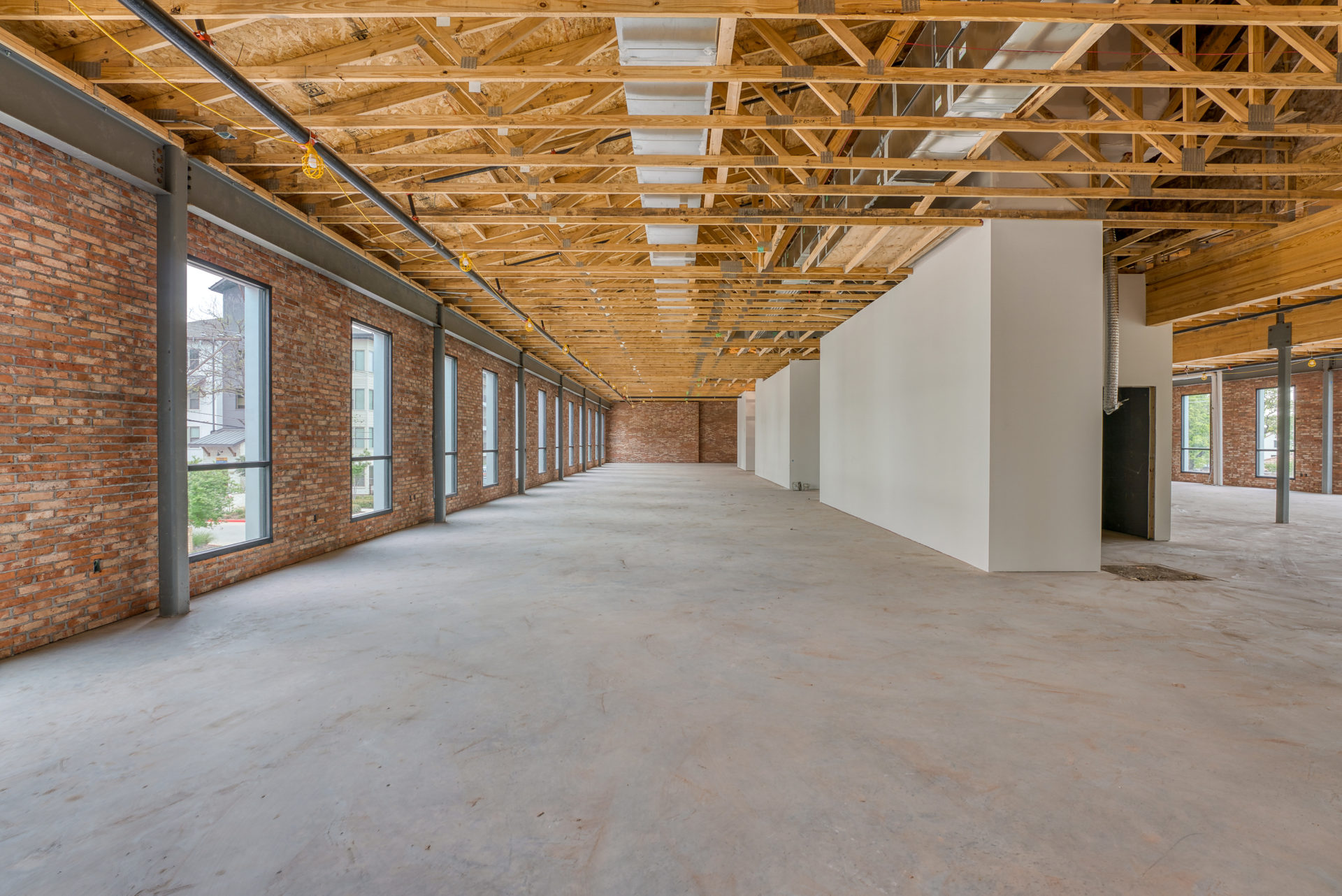 Interior view of second floor of 133 Nursery Lane with a brick wall on the right side and steel beams throughout